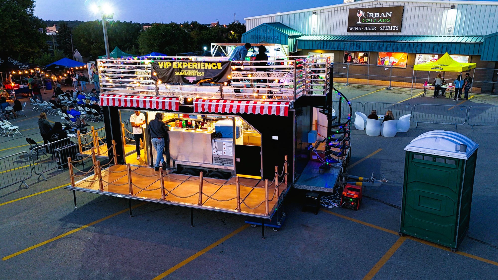 Cocktail Caravan bar trailer lit up at dusk with a rooftop deck and open service bar