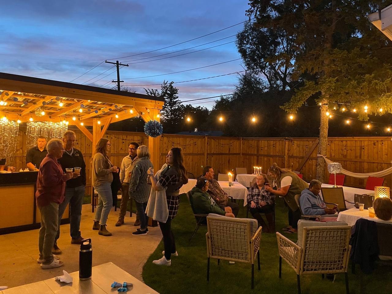 Backyard party at dusk with guests gathered around the pop-up bar